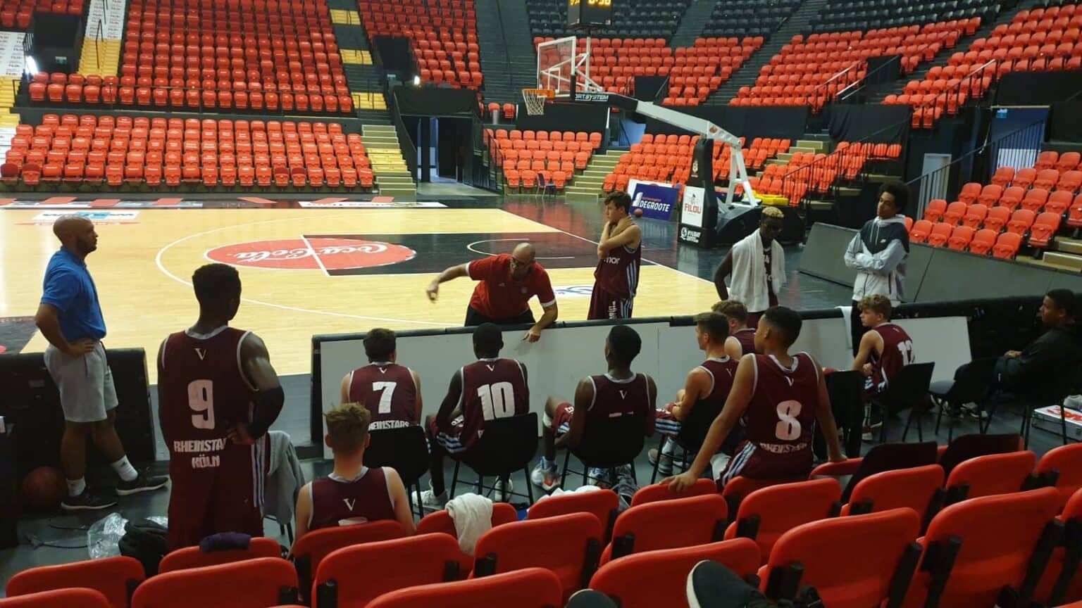 RheinStars Köln Basketballmannschaft sitzt auf der Bank während eines Spiels in der Halle.