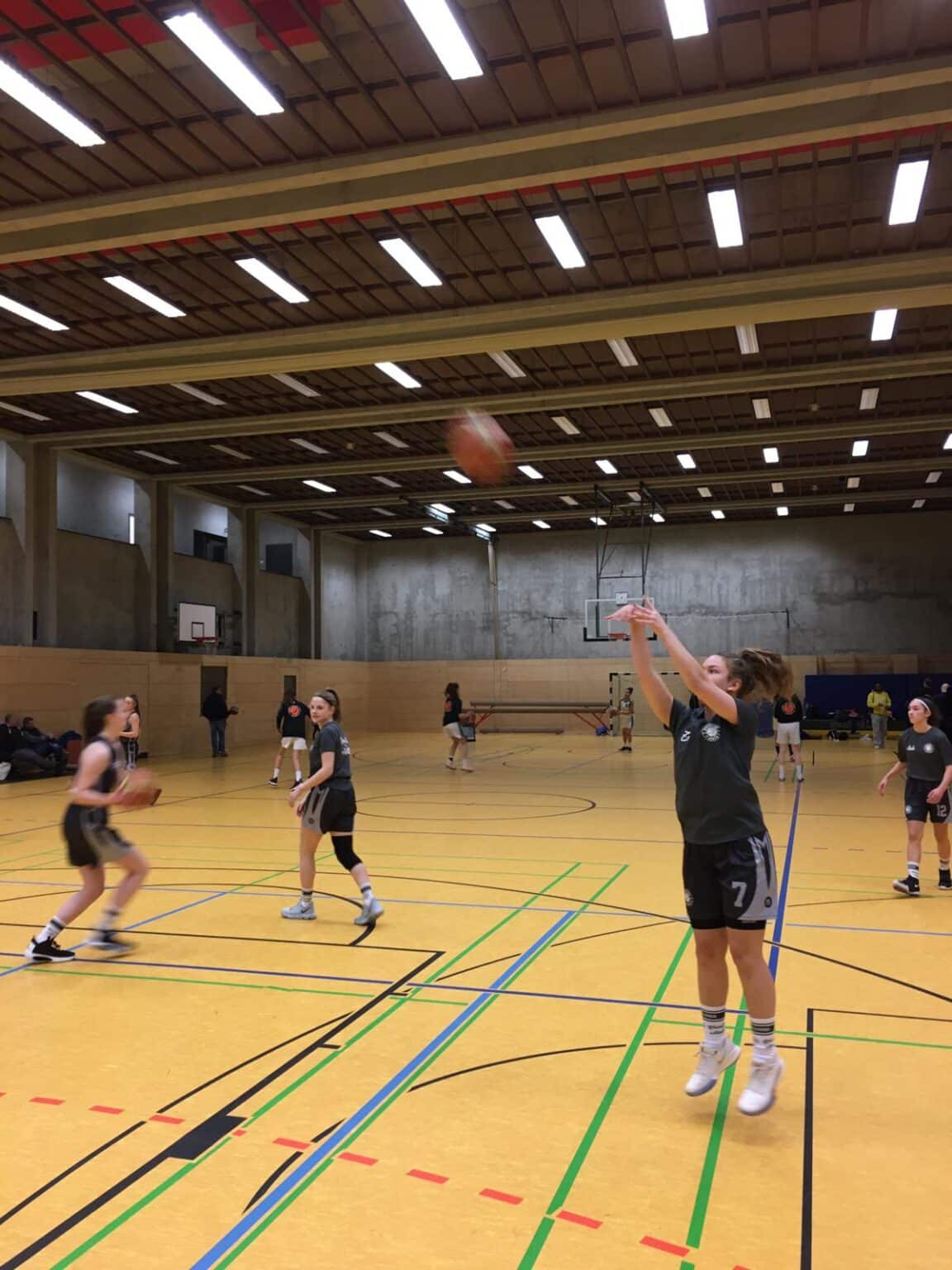 Basketballtraining der RheinStars Köln in einer Sporthalle mit Spielerinnen beim Wurf- und Passtraining.