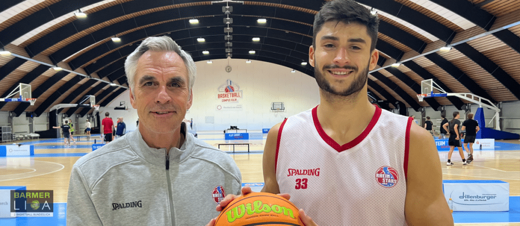 Zwei Personen halten einen Basketball in einer Sporthalle der RheinStars Köln.