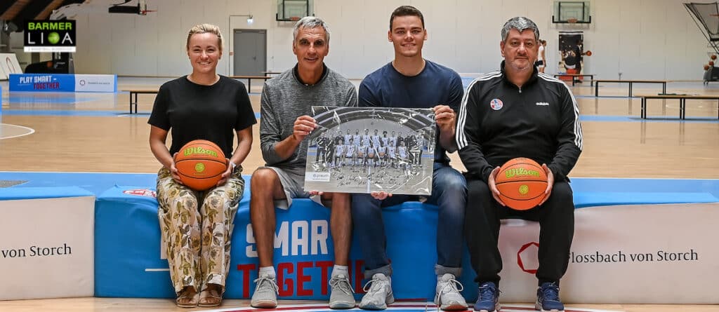Vier Personen halten Basketbälle und ein Schwarzweißfoto in einer Sporthalle der RheinStars Köln.