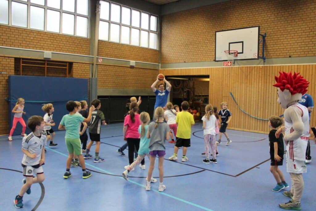 Kinder spielen Basketball in einer Sporthalle der RheinStars Köln.