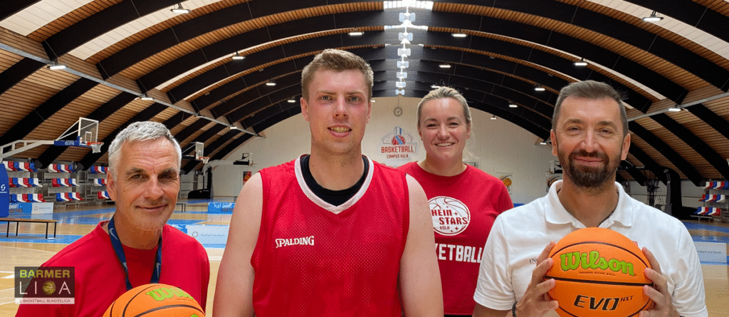 Vier Personen der RheinStars Köln halten Basketbälle in einer Sporthalle.