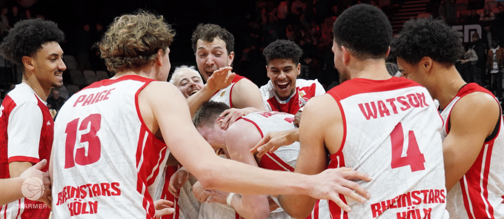Basketballteam RheinStars Köln jubelt zusammen auf dem Spielfeld.