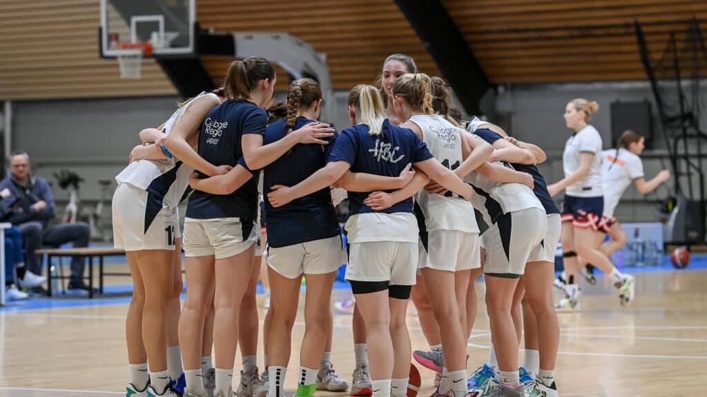 Basketballteam der RheinStars Köln im Motivationskreis während eines Spiels in der Sporthalle.