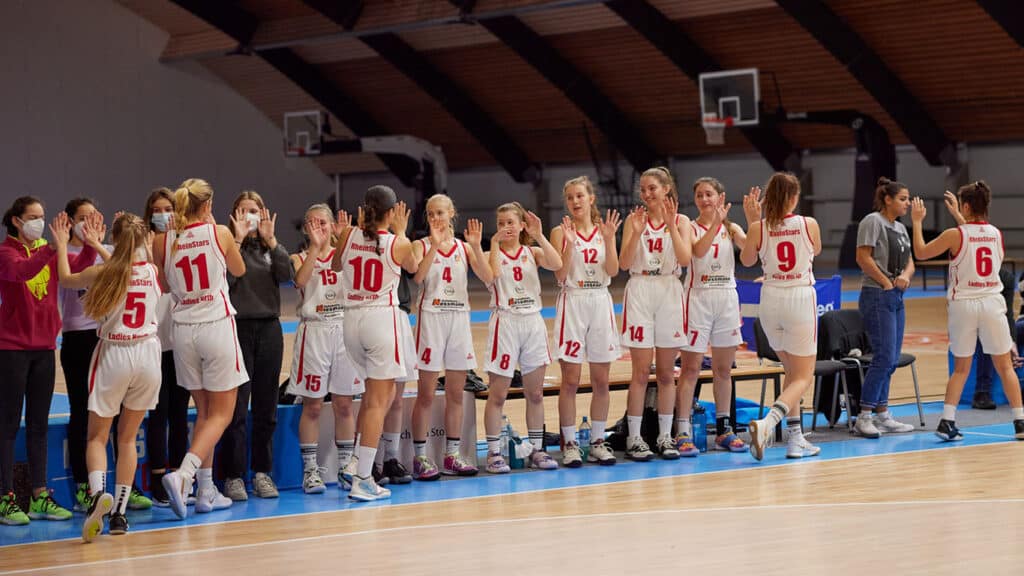 Frauenbasketballmannschaft RheinStars Köln in weißen Trikots steht Spalier in der Halle.