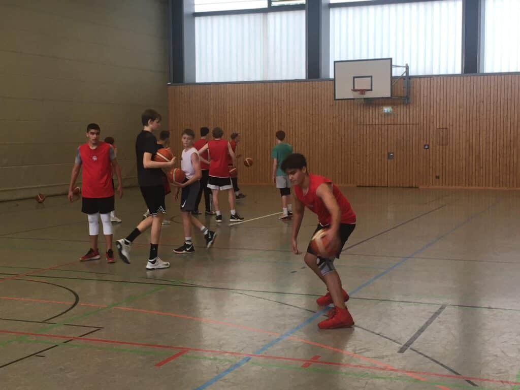 Basketballtraining der RheinStars Köln in einer Sporthalle mit Spielern in roten Trikots.
