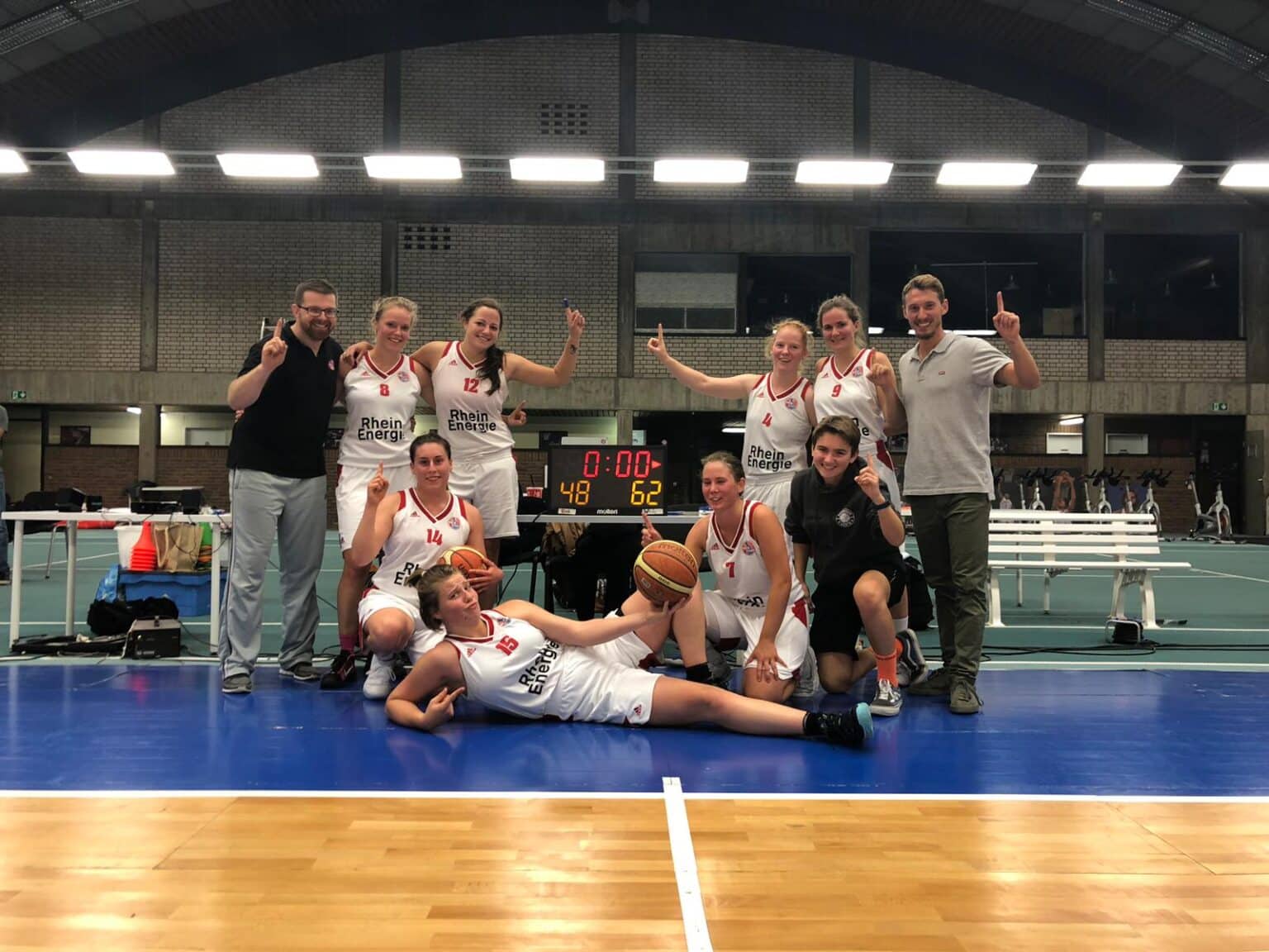 Basketballteam RheinStars Köln jubelt nach Sieg in Sporthalle.