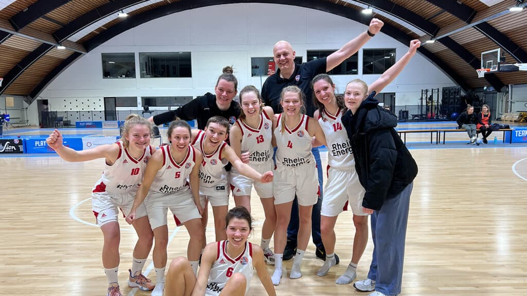 Basketballteam der RheinStars Köln jubelt nach Sieg in der Sporthalle.