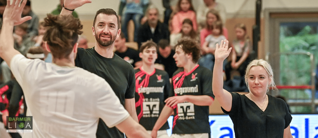 Spieler und Trainer der RheinStars Köln jubeln gemeinsam in der Sporthalle.