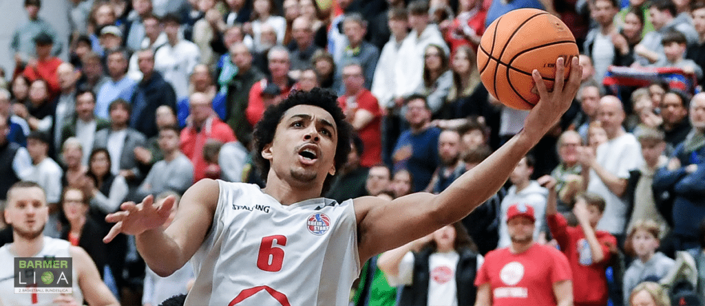 Basketballspieler der RheinStars Köln mit Nummer 6 beim Wurf vor Zuschauern.