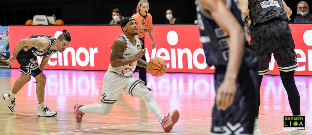 Basketballspieler der RheinStars Köln dribbelt in weißem Trikot während eines Heimspiels.