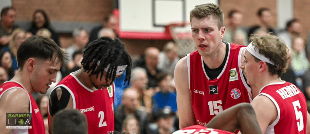 Basketballspieler der RheinStars Köln im roten Trikot während eines Spiels in der Halle.