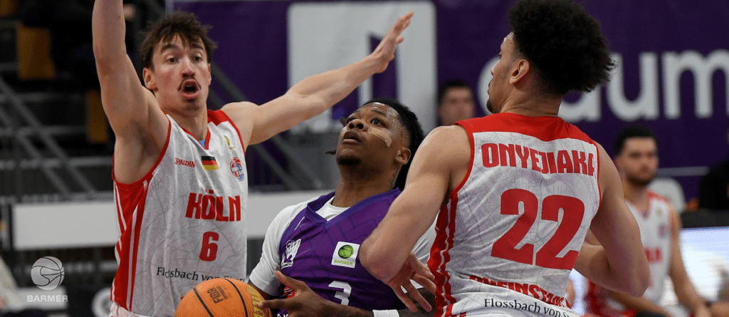 Basketballspiel: RheinStars-Spieler verteidigen gegen Gegner in Purpur.