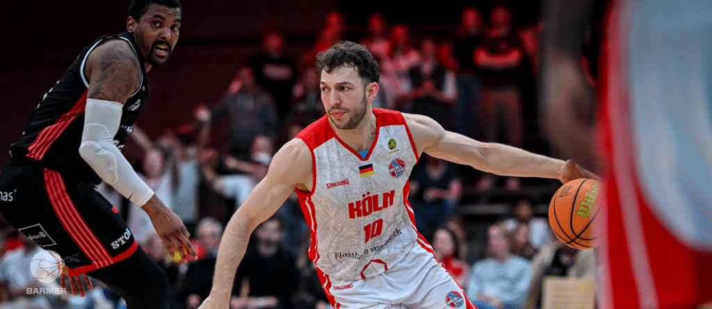 Basketballspieler der RheinStars Köln dribbelt Ball während Spiel gegen gegnerisches Team.
