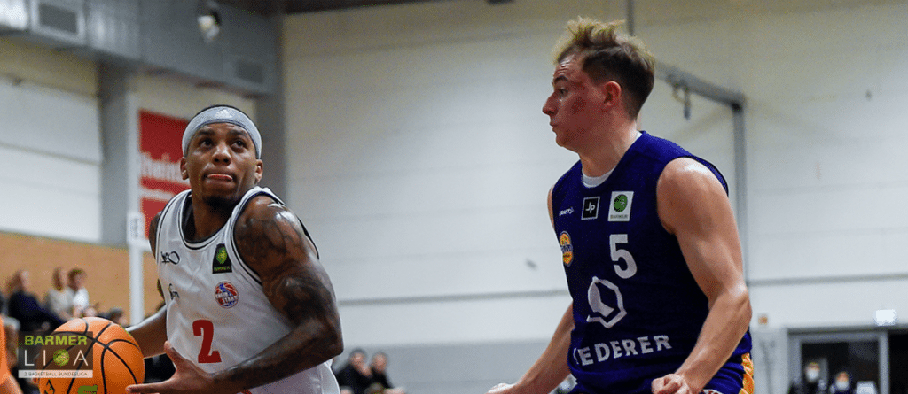 Basketballspiel der RheinStars Köln: Spieler Nummer 2 in weißem Trikot gegen Gegner Nummer 5 in dunklem Trikot.