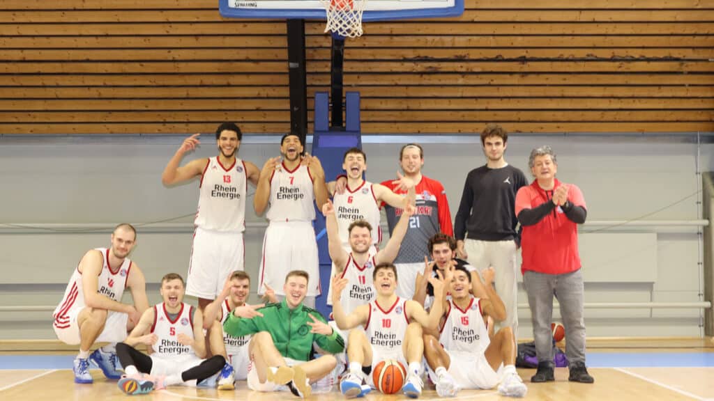 Basketballmannschaft RheinStars Köln jubelt gemeinsam in der Sporthalle.