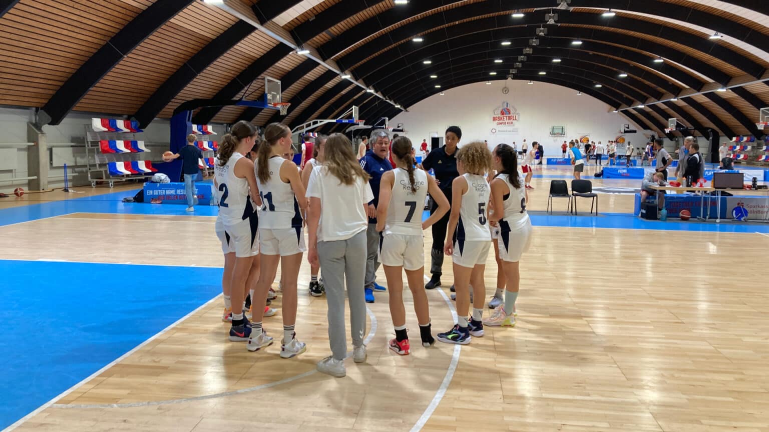 Mädchen-Basketballteam der RheinStars Köln in Trainingshalle beim Mannschaftskreis.