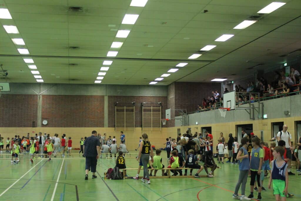 Sporthalle mit Basketballspiel der RheinStars Köln, Zuschauer auf der Tribüne.