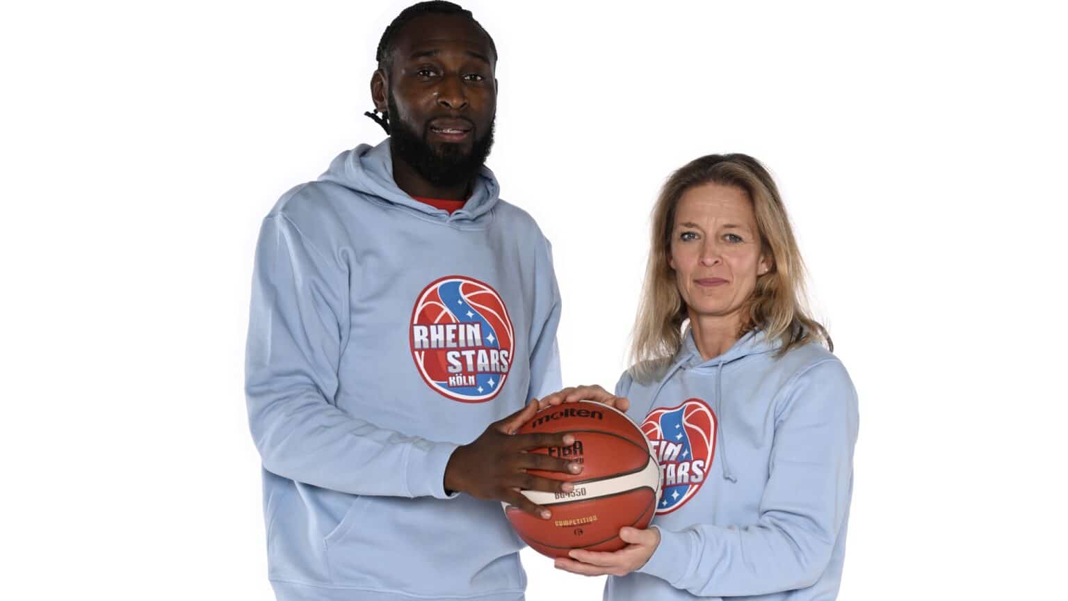 Zwei Personen in RheinStars Köln Hoodies halten gemeinsam einen Basketball.
