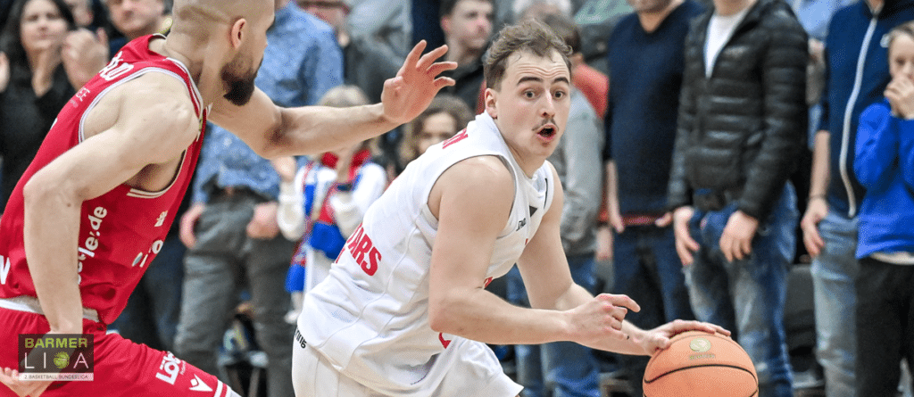 Basketballspieler der RheinStars Köln dribbelt gegen roten Gegner.