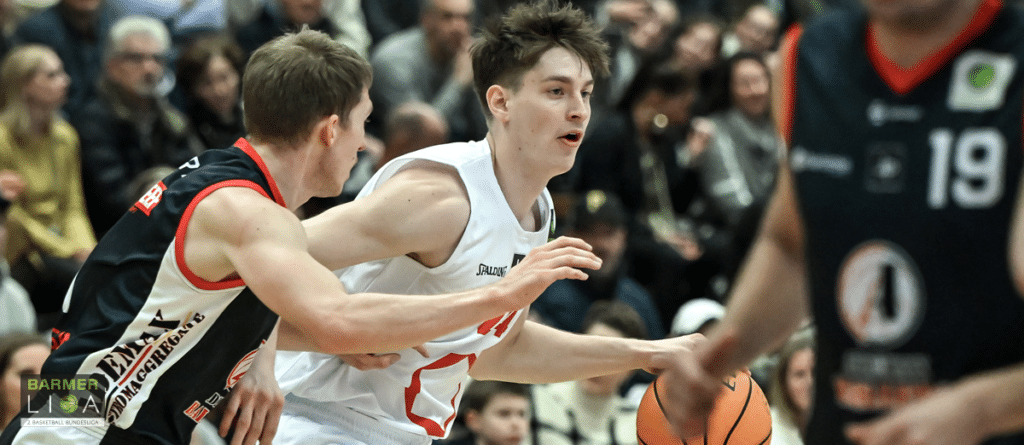 Basketballspieler der RheinStars Köln in weißem Trikot dribbelt gegen Gegner in schwarzem Trikot.
