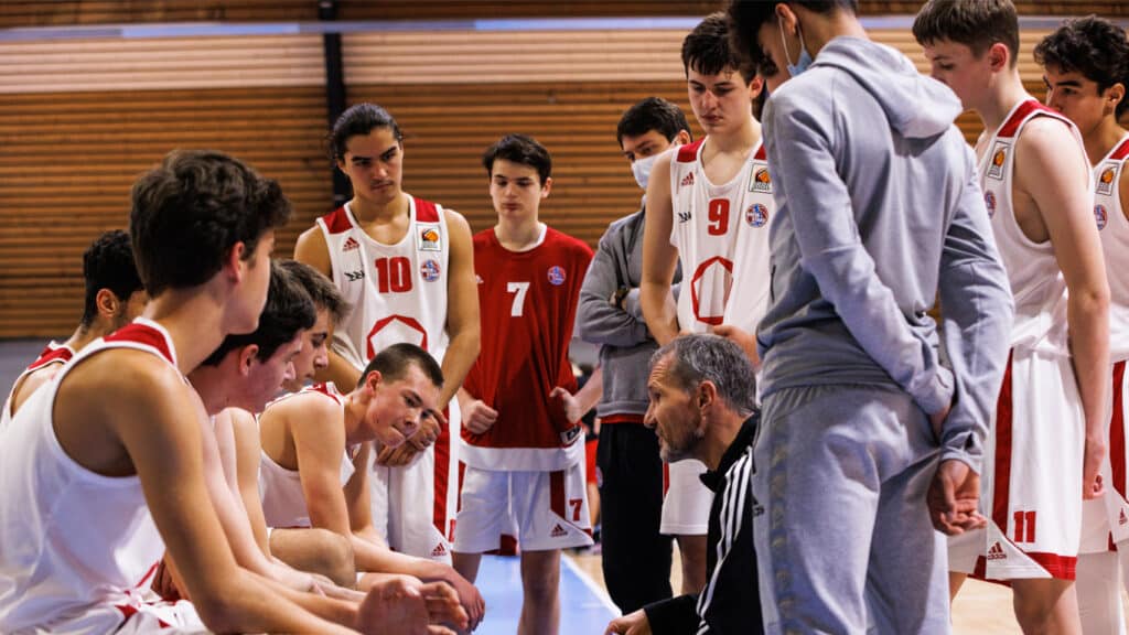 Trainer spricht zu Basketballteam der RheinStars Köln in Sporthalle während Spielerpause.