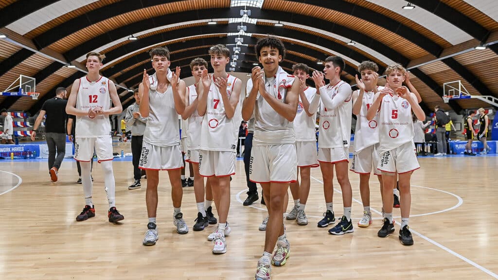 Basketballmannschaft der RheinStars Köln klatscht nach Spiel in moderner Sporthalle.