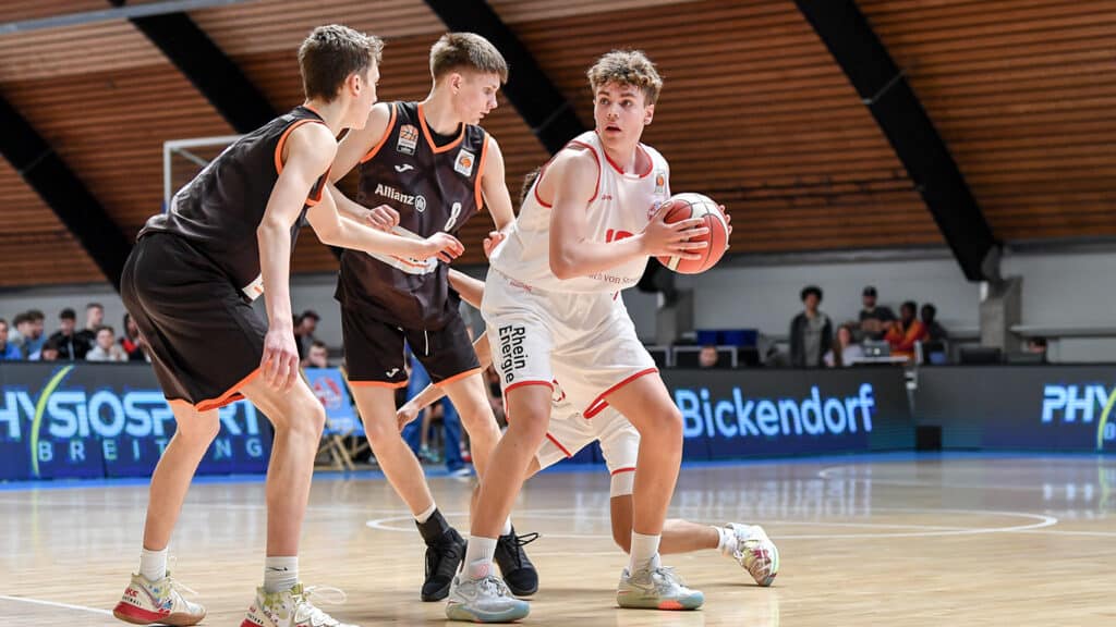 Basketballspiel der RheinStars Köln: Spieler in weißem Trikot dribbelt gegen Verteidiger in schwarzem Trikot.