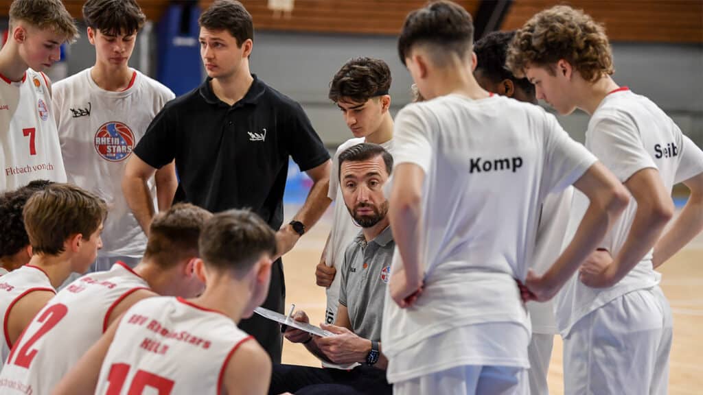Trainer der RheinStars Köln gibt Anweisungen an seine Basketballmannschaft während einer Spielpause.