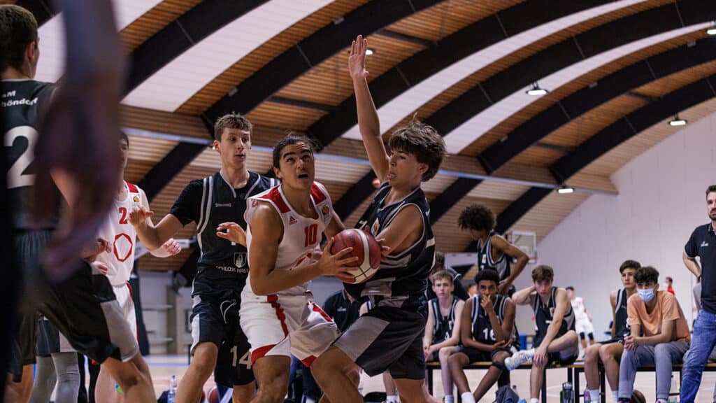 Basketballspiel der RheinStars Köln: Spieler in weißem Trikot mit Nummer 10 dribbelt gegen Verteidiger in schwarzem Trikot.