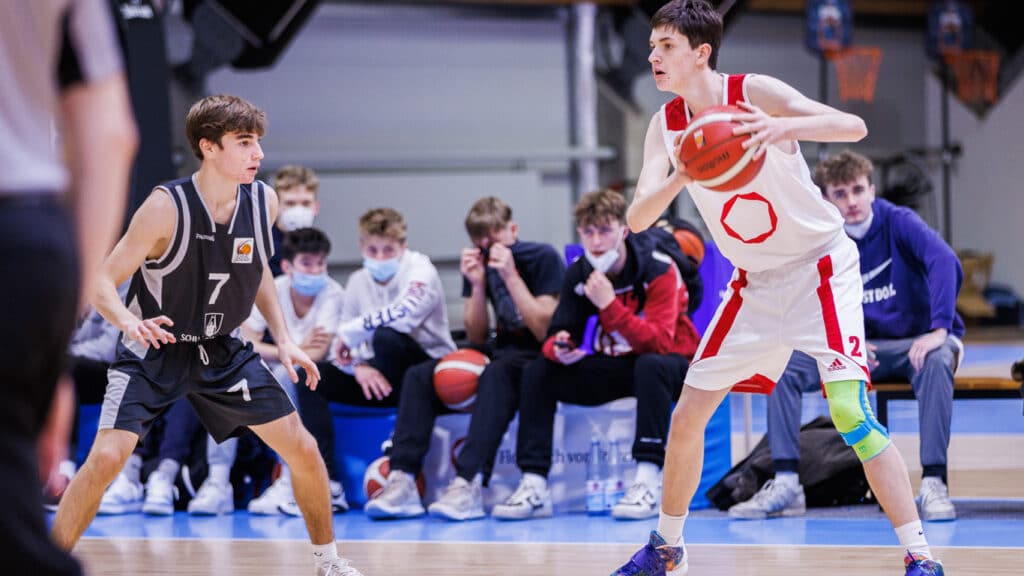 Basketballspiel der RheinStars Köln: Spieler in rotem Trikot mit Ball gegen Verteidiger in schwarzem Trikot.
