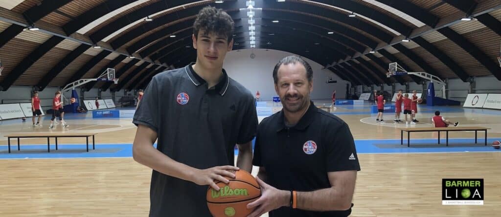 Zwei Männer halten einen Basketball in einer Sporthalle der RheinStars Köln.