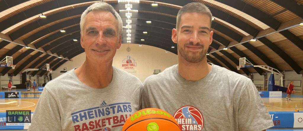 Zwei Männer halten einen Basketball in der RheinStars-Köln-Halle.