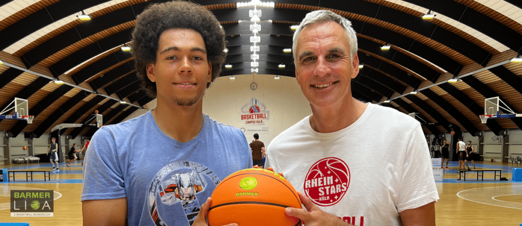 Zwei Personen halten einen Basketball in einer Sporthalle der RheinStars Köln.