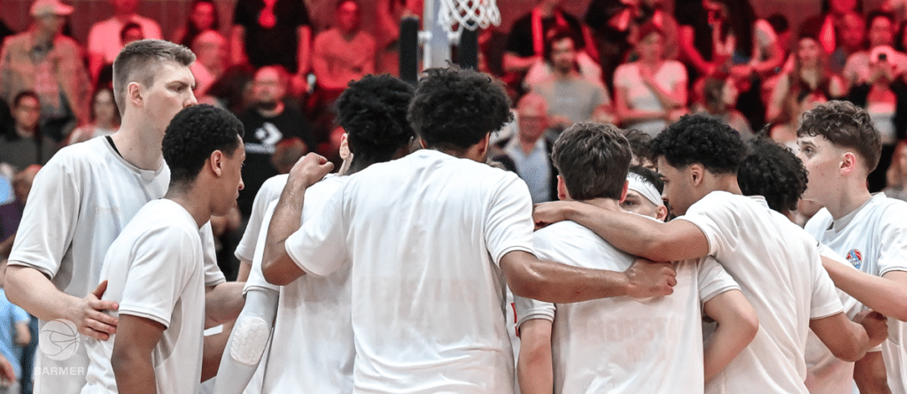 Basketballmannschaft RheinStars Köln im Teamkreis während eines Heimspiels vor Publikum.