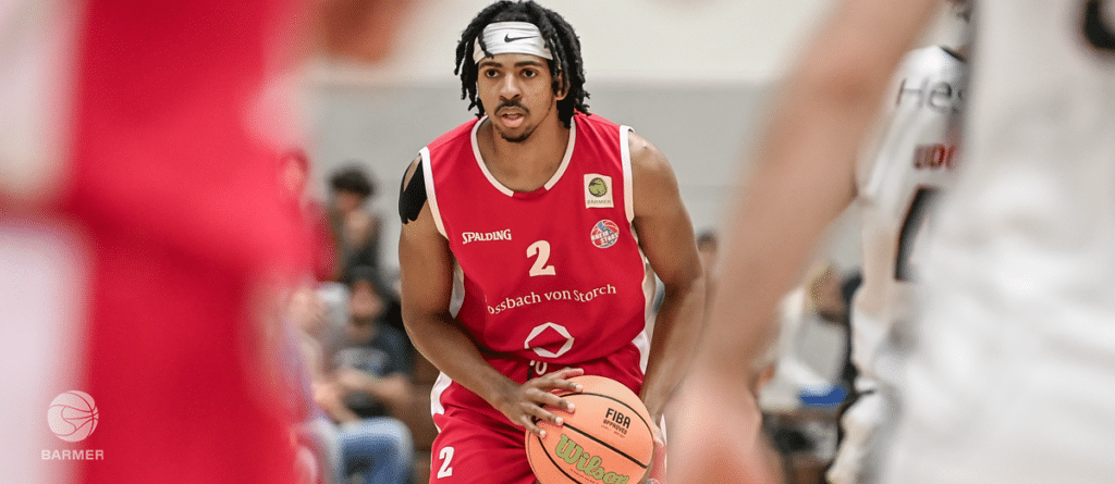 Basketballspieler der RheinStars Köln trägt rotes Trikot mit Nummer 2 und dribelt den Ball.