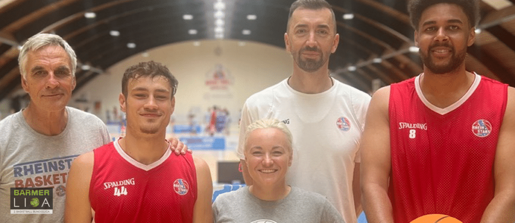 Fünf Personen der RheinStars Köln posieren zusammen in einer Sporthalle.