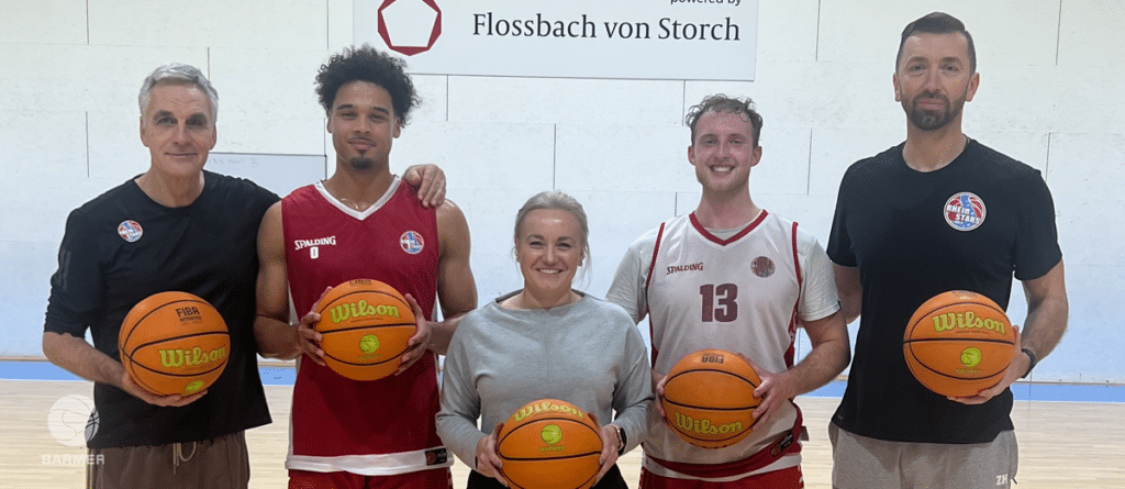 Fünf Basketballer der RheinStars Köln halten Wilson-Basketbälle in einer Sporthalle.