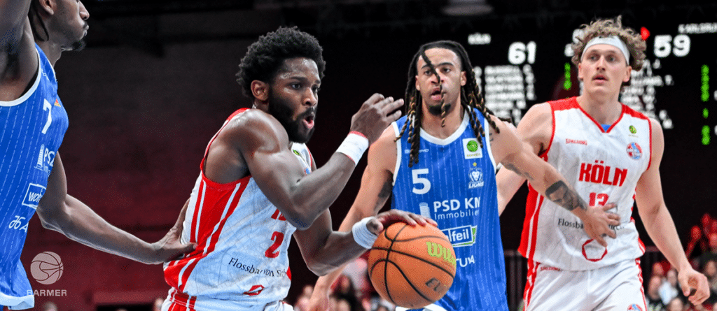 Basketballspiel der RheinStars Köln gegen gegnerisches Team in roter und blauer Sportkleidung.