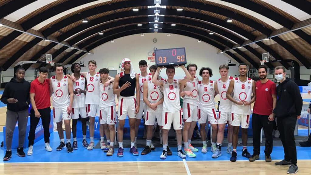 RheinStars Köln Basketballmannschaft posiert nach Sieg in Sporthalle, Anzeigetafel zeigt 93:90.