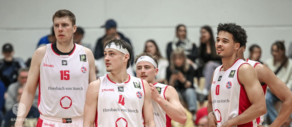 Basketballspieler der RheinStars Köln in weißen und roten Trikots während eines Spiels in der Halle.
