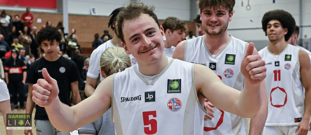Basketballspieler der RheinStars Köln zeigen Daumen hoch nach Spielende in der Halle.