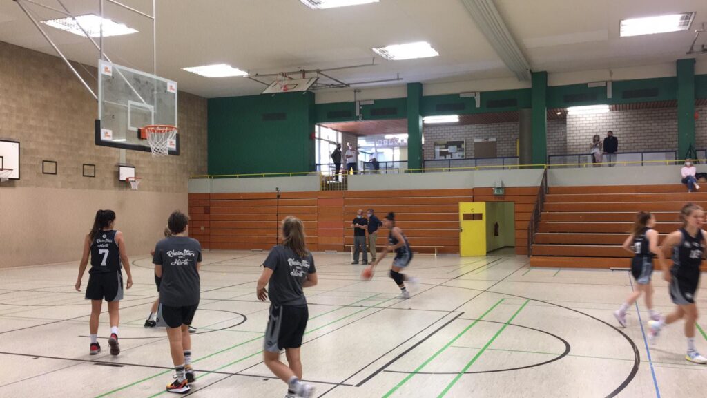 Basketballtraining der RheinStars Köln in einer Sporthalle mit Spielerinnen in schwarzen Trikots.