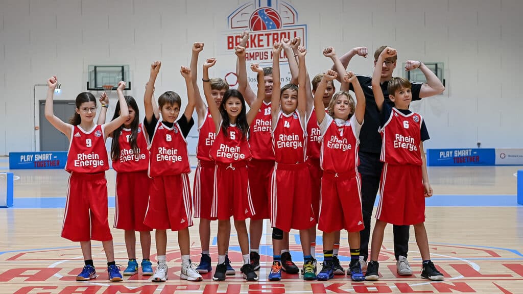 Basketballteam der RheinStars Köln jubelt mit erhobenen Fäusten in der Sporthalle.