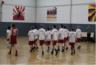 Basketballmannschaft der RheinStars Köln in weißen Trikots steht im Kreis in einer Sporthalle.