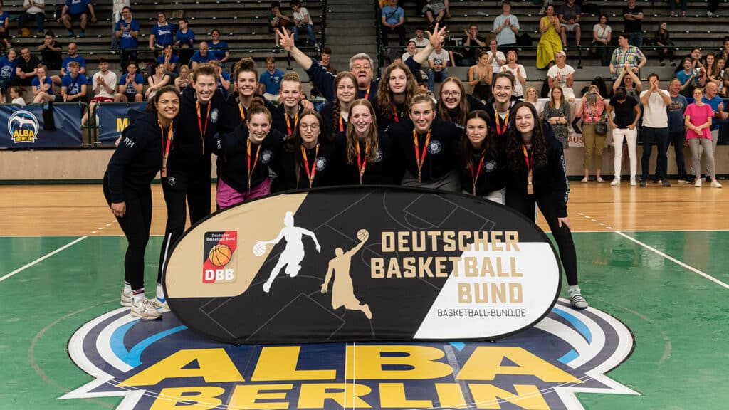 Basketballmannschaft der RheinStars Köln mit Medaillen posiert vor Publikum in der Alba-Berlin-Halle.