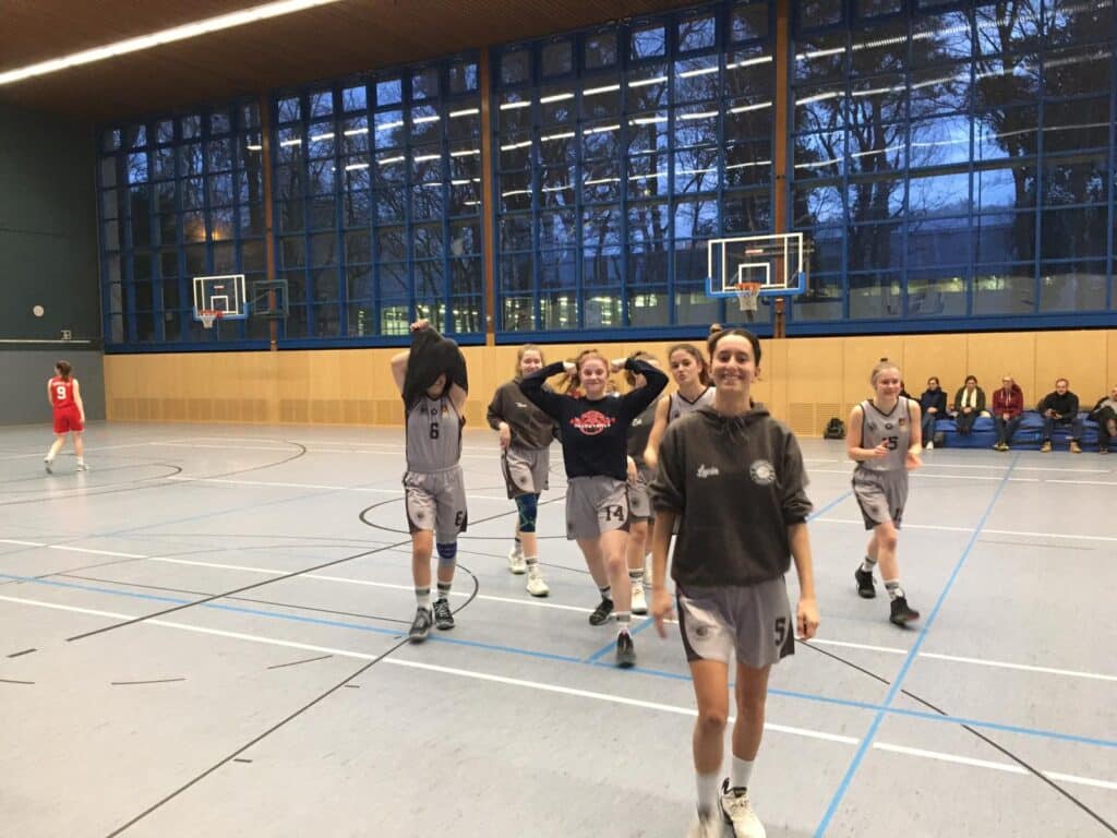Basketballmannschaft der RheinStars Köln jubelt in der Sporthalle nach Spielende.