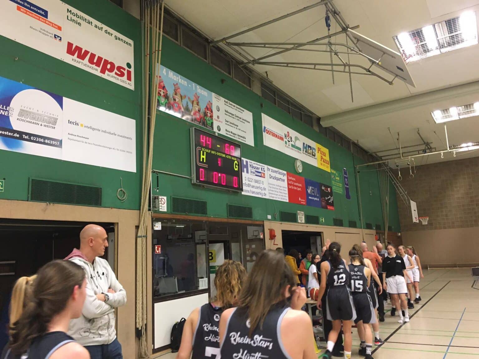 Sporthalle mit RheinStars-Kölner Basketballteam, Trainer und Spielerinnen beim Training.