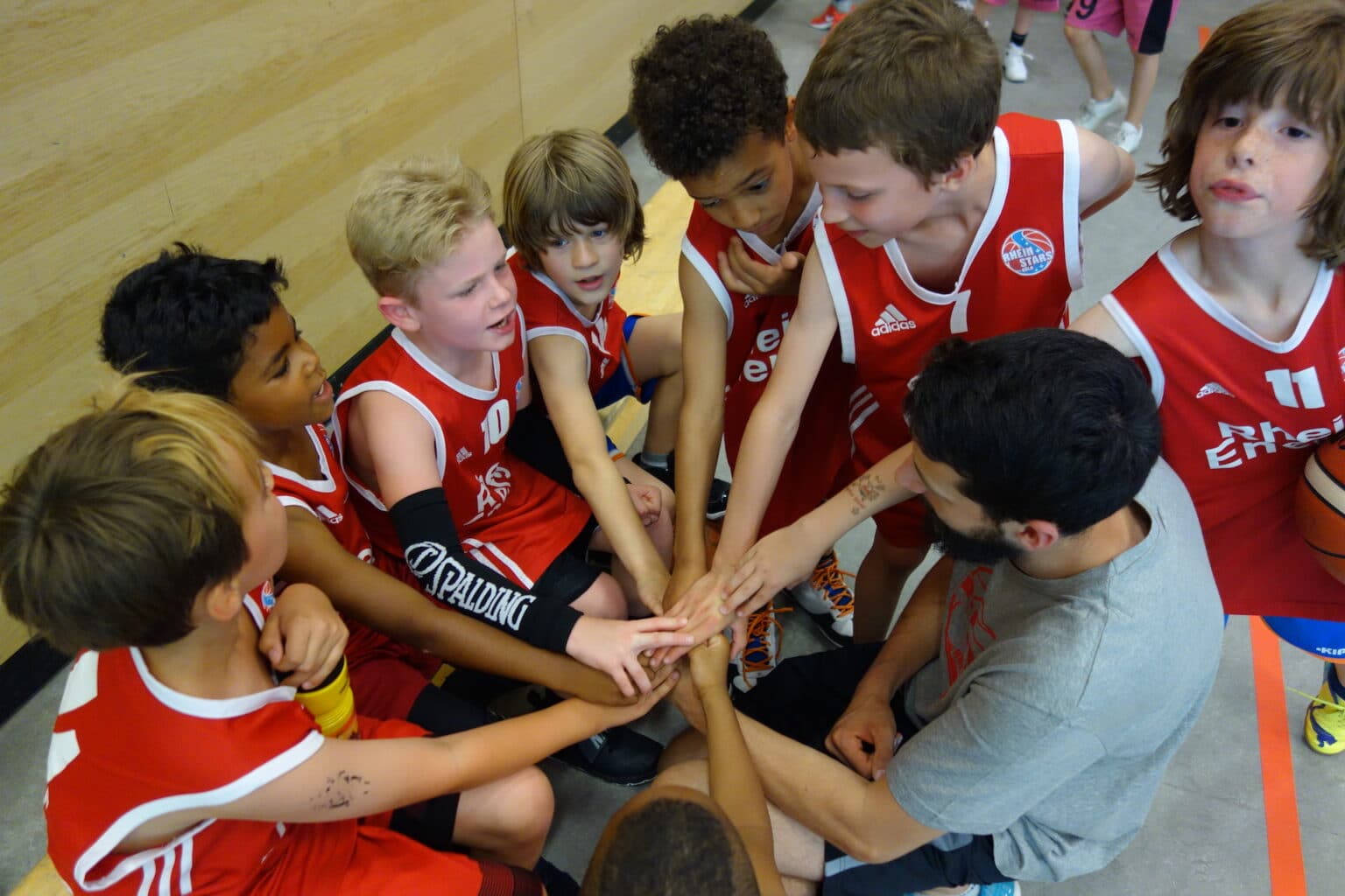 Junge Basketballspieler der RheinStars Köln legen ihre Hände zusammen zum Teamgruß.