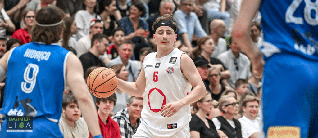 Basketballspieler der RheinStars Köln in weißem Trikot mit Nummer 5 dribbelt den Ball während eines Spiels.